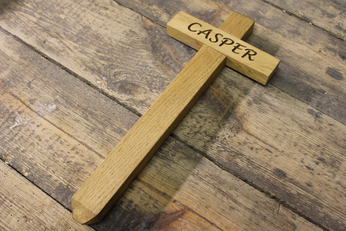 Wooden cross with 'Casper' engraved on it, placed on a wooden surface. Memorial Cross