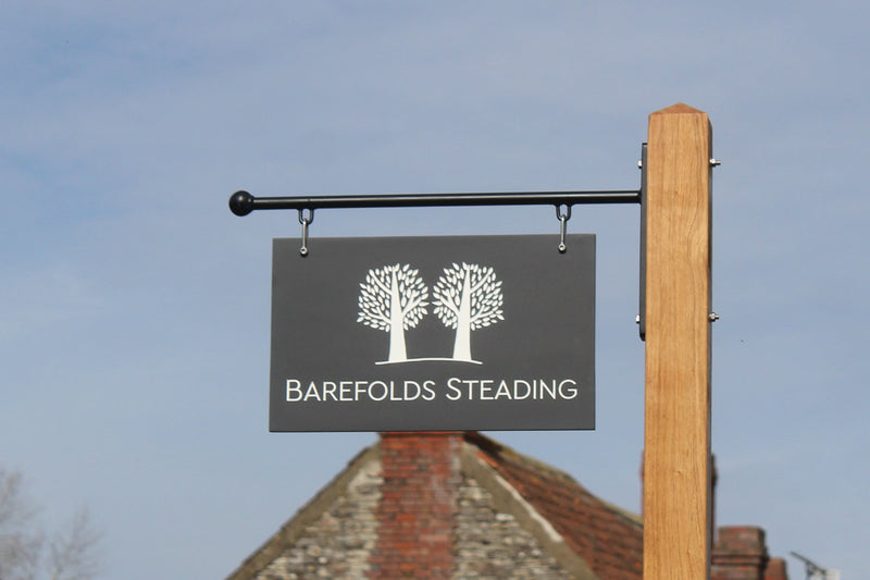 Corian Hanging Sign against a blue sky.  Oak post and metal bracket